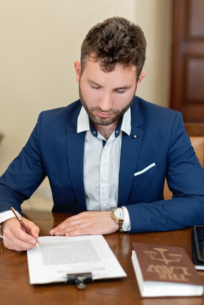pexels-photo-8729731 A businessman in formal attire signs a legal document at an office desk, emphasizing professionalism.